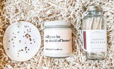 Make the most of your proposal and send her this “will you be my maid of honor?” gift set.  She will love the This gift set includes one “will you be my maid of honor?” soy candle, white + gold trinket jewelry dish and safety matches.  